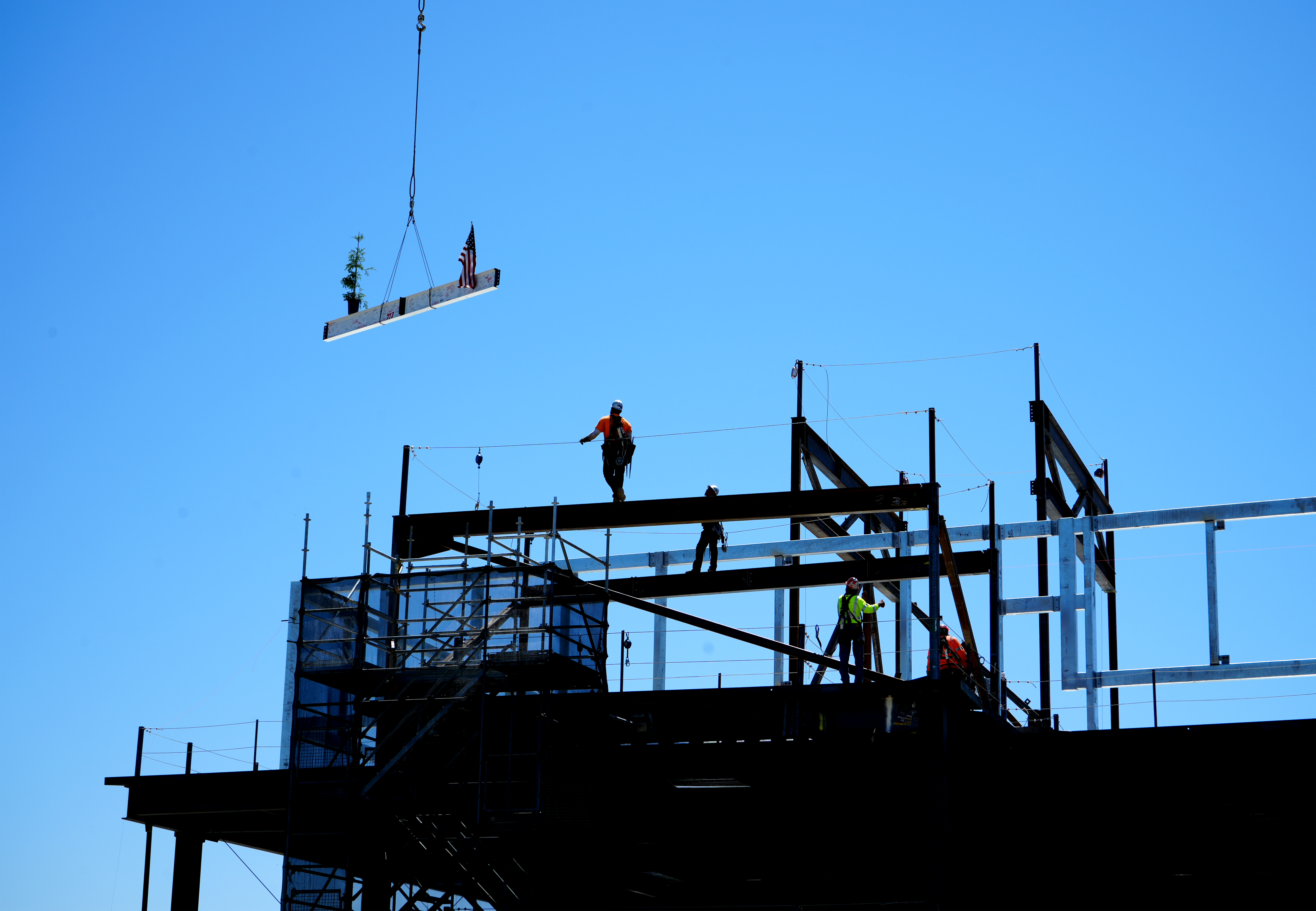 A crane lowering the final steel beam to ironworkers at 48X.